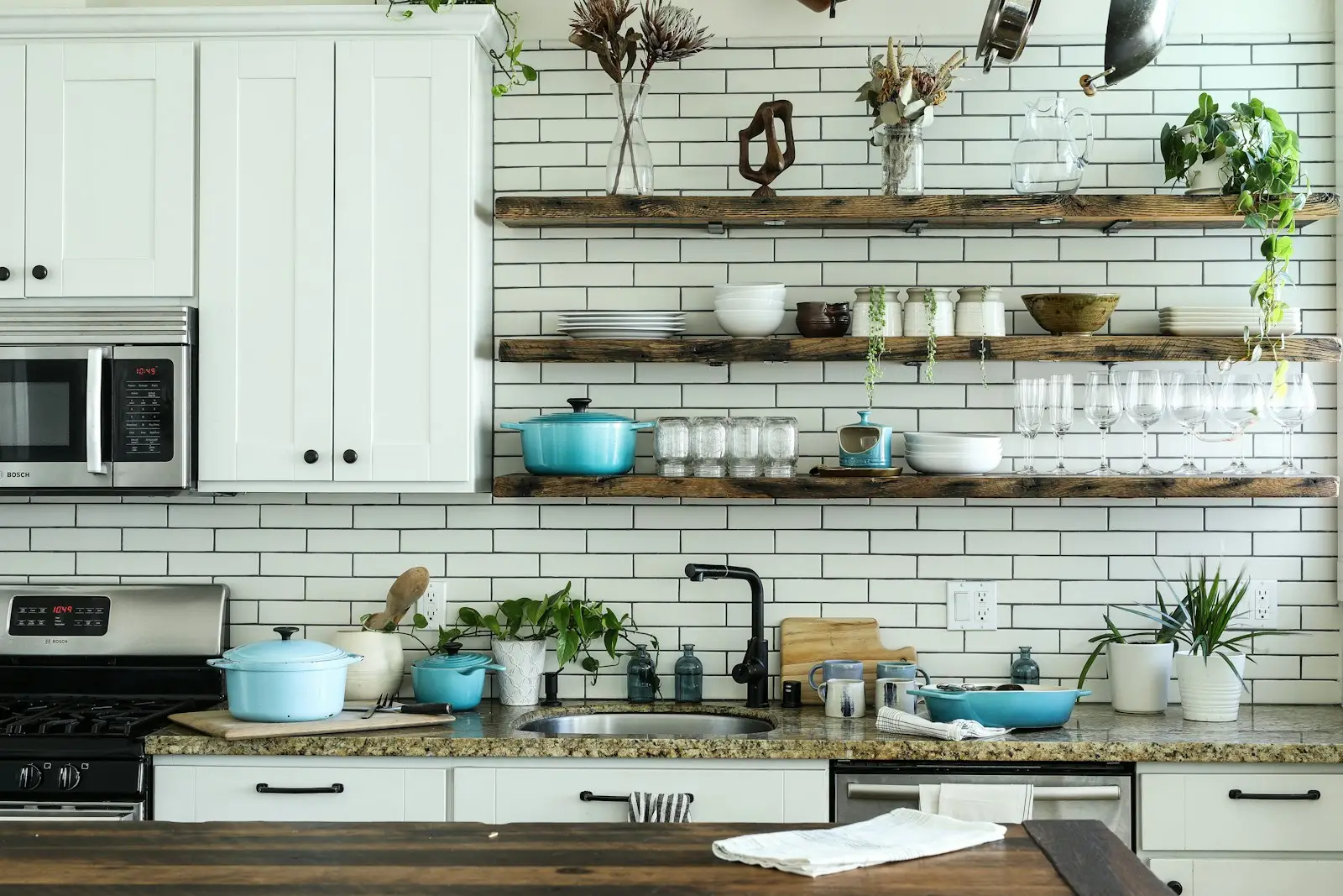 A clean kitchen with white cabinets and wooden shelves